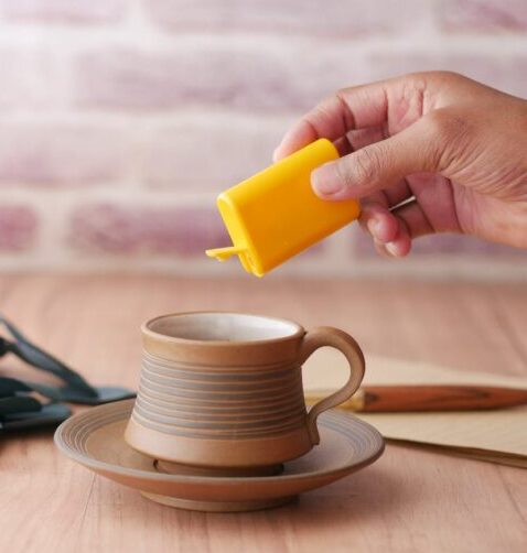 unrecognizable male hand adding sweetener to cup of coffee