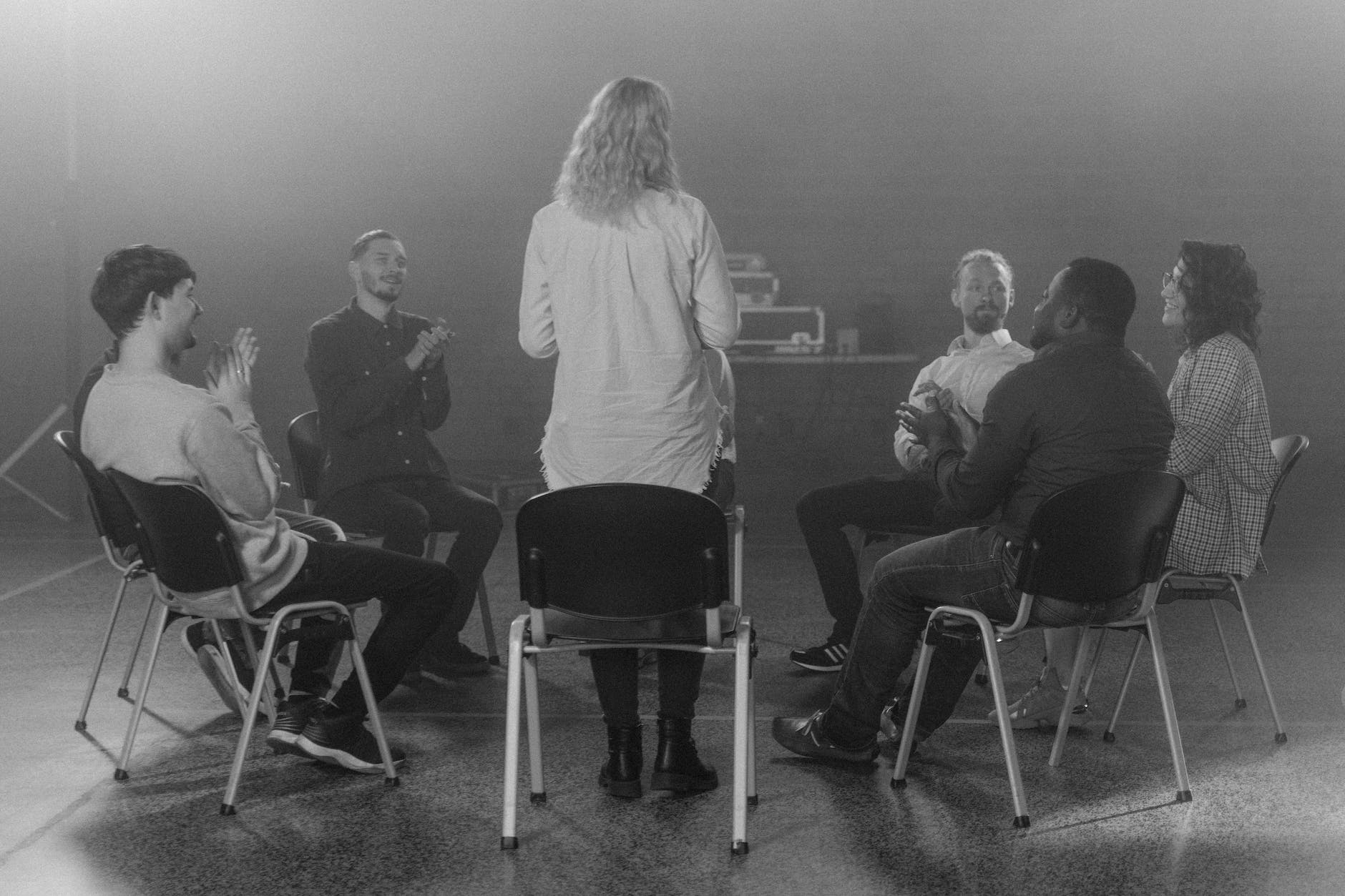 woman standing beside a group of people sitting on chairs