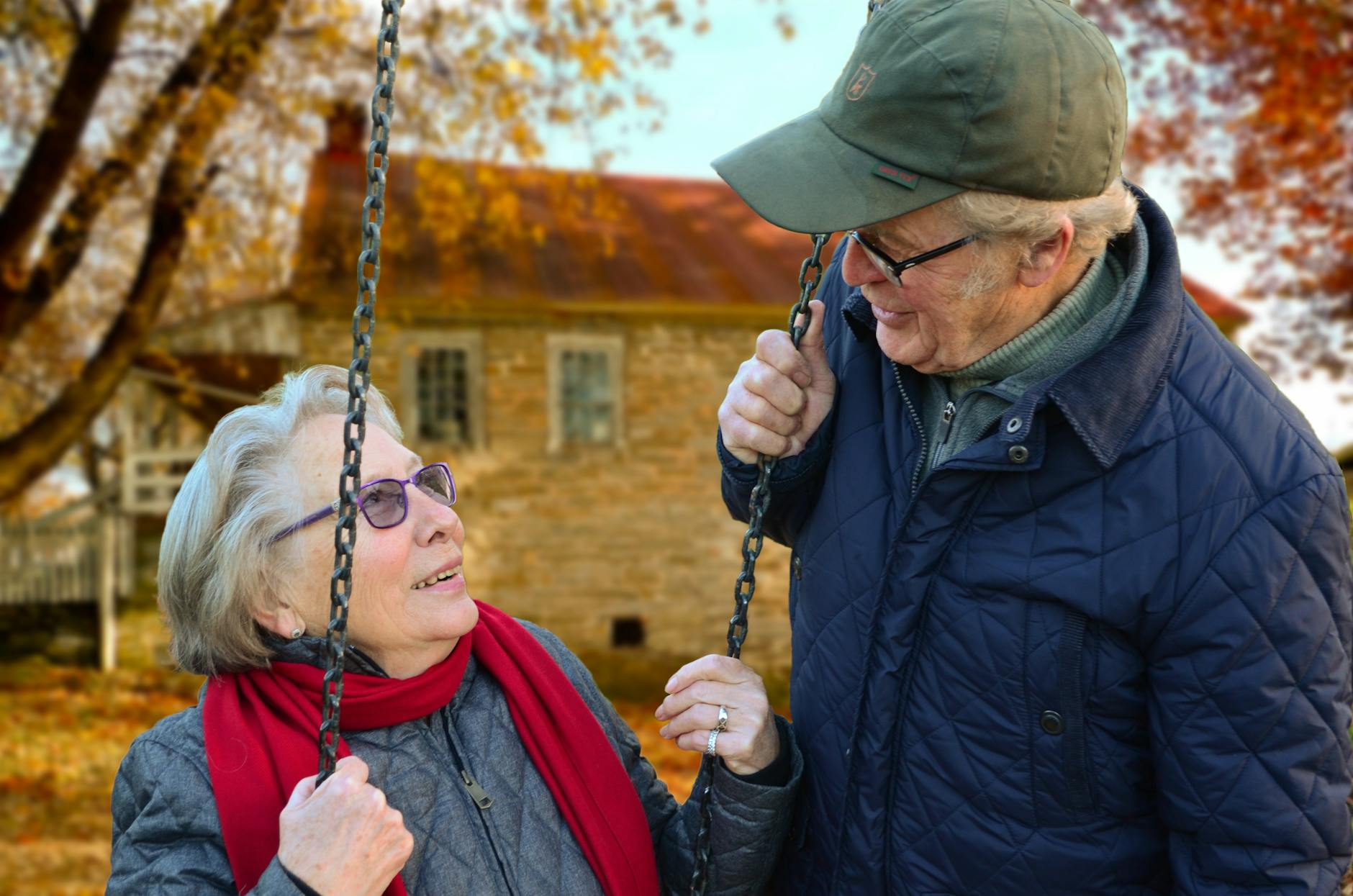 man standing beside woman on swing